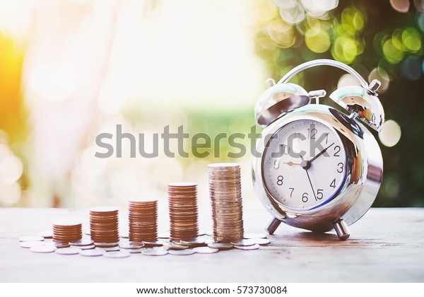 Close up of time and money with green bokeh\
background ,Business Finance and Money concept,Save money for\
prepare in the future.time is money\
concept