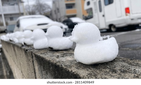 Close up of a tiny snow duck with a row of snow figures fading into the winter background