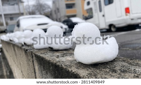 Close up of a tiny snow duck with a row of snow figures fading into the winter background