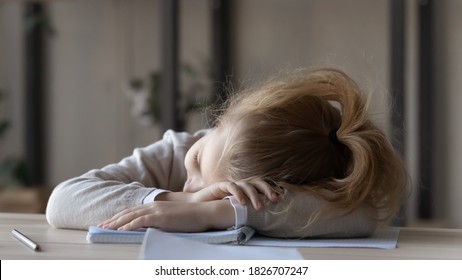 Close Up Tired Little Girl Sleeping At Work Desk, Lying On Notebooks, Exhausted Child Schoolgirl Feeling Lazy And Unmotivated, Doing Boring School Homework Assignments, Sitting At Table At Home