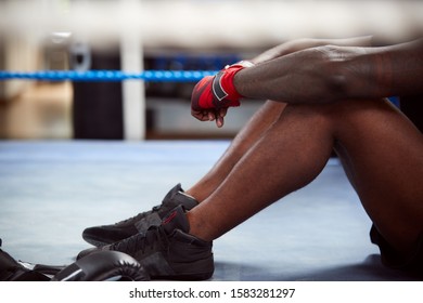 Close Up Of Tired Male Boxer Sitting In Boxing Ring In Gym After Training Session