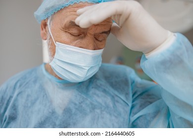 Close Up Of Tired Surgeon In Mask Standing In Operating Room After Major Surgery