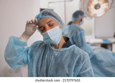 Close Up Of Tired Surgeon In Mask Standing In Operating Room After Major Surgery