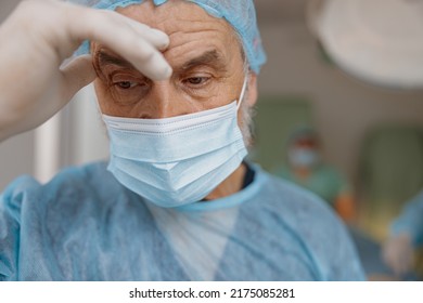 Close Up Of Tired Surgeon In Mask Standing In Operating Room After Major Surgery