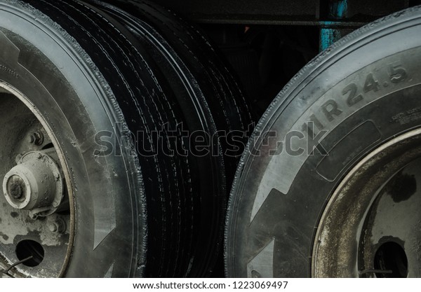 up\
close to the tires of a cargo truck, black tires with dirt caused\
by rain in a city, from the inside of a car in\
motion