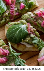 close up of a toasted slice of flat bread topped with a home made spread using avocado and fermented cabbage and then topped with fresh greens.