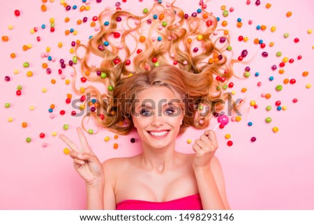 Close up top above high angle view photo beautiful she her lady show v-sign lying down sweets ideal hair colored little candies trying lolly pop wearing classy chic dress isolated pink background