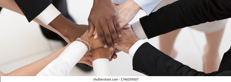 Close up top above view group of multi ethnic business people stacked palms together as concept of corporate unity, connection, team building loyalty. Horizontal photo banner for website header design