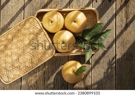 Close up and top angle view of four yellow pear fruits with leaf on side-dish box with lid on wood floor, South Korea
