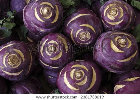 Close up and top angle view of stacked raw kohlrabi with purple roots for sale in a traditional market, South Korea
