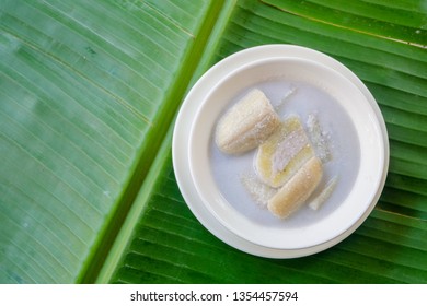 Close Up And Top View : Banana In Coconut Milk (Thai Popular Dessert) In White Bowl  On Green Banana Leaf Background. 