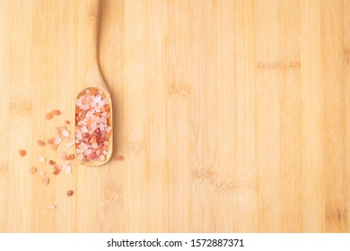 Close up top view of beautiful pinkish Himalayan salt rock in a wooden tea scoop on the table. The salt is mined in Pakistan and has very rich mineral benefit for health and skin. Salt Therapy spa. - Powered by Shutterstock