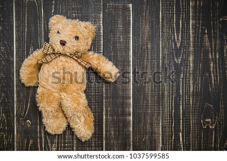 Close up top view of cute soft brown teddy bear laying on wooden shabby background. Horizontal color photography.