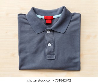 Close Up Top View Of Deep Gray Polo Shirt Put On Brown Wooden Table Top