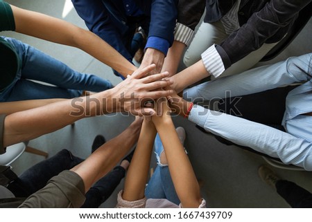 Close up top view of diverse businesspeople stack hands motivated for shared business success at briefing, multiracial colleagues engaged in teambuilding activity show unity support at office meeting