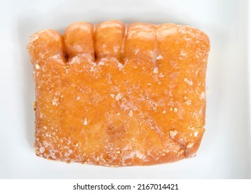 Close Up Top View Flat Lay Of One Bear Claw Donut On A Fancy Off White Porcelain Plate, Isolated On White. A Yeast Donut Shaped Like A Bear Claw. Filled With Apple Fruit And Covered In Sugar Glaze.