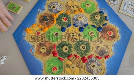 Close up top view flat lay of the popular strategic economic board game Settlers of Catan. Concept: entertainment in the family and with friends, hobbies, free time, weekends