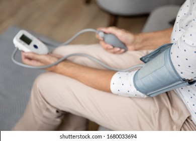 Close Up Top View Focus On Elder Woman Upper Arm Bicep In Cuff. Older Retired Lady Measuring Manually Blood Pressure, Using Digital Tonometer Machine At Home. Healthcare, Disease Treatment Concept.