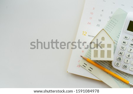 close up top view group of calculator , home model ,yellow pencil, banking account book and calendar on white color background with space for money management ,home loan and personal financial concept