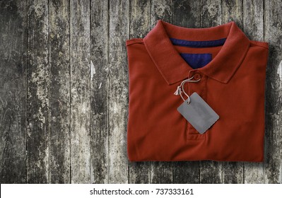 Close Up Top View Of Man Polo Shirt Put On Rustic Wooden Table Top With Blank Space Use For Texts Display