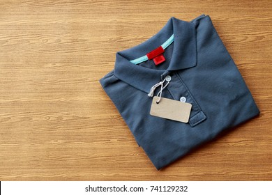 Close Up Top View Of Man Polo Shirt Put On Rustic Wooden Table Top With Blank Space Use For Texts Display