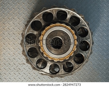 Close up top view of a metal cycloidal gear reducer with roller bearing on diamond plate steel background. Heavy machinery spare part, industrial equipment, mechanical engineering and manufacturing concept.