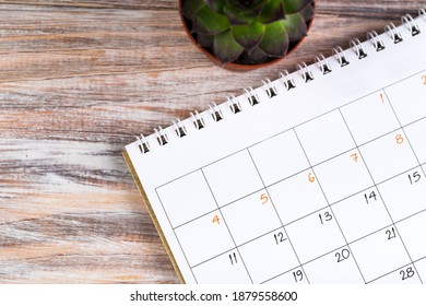 close up top view on white calendar for 2021 month schedule to make an appointment or manage schedule every day on wooden table with potted plant, succulent plant for work planning and life concept - Shutterstock ID 1879558600