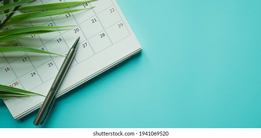 close up top view on white calendar 2021 with pencil and tropical leaves on blue color table background for planning work and life balance in holiday summer concept