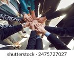 Close up top view photo of diverse business people putting their arms together. Stack of hands of a group of multiethnic company employees. The concept of unity, partnership and teamwork.