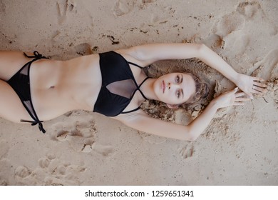 Close Up Top View Of A Smiling Woman Lying On Beach Sand Relaxing On Beach.