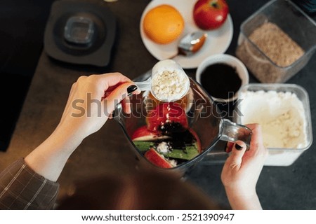 Close up top view woman adding plant based pea protein powder during making smoothie on the kitchen. Superfood supplement. Healthy nutritional vegan diet. Healthy dieting eating, weight loss program.