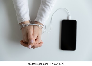 Close up top view of woman hands connected with wire cable to smartphone gadget, female bound addicted to cellphone device, dependent on social media, internet technology, addiction concept - Shutterstock ID 1716918073