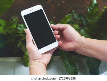 Close up top view of a wrinkled hands of elderly usinging a smart phone