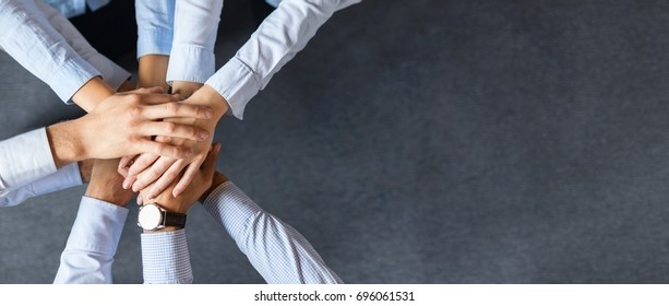 Close up top view of young business people putting their hands together. Stack of hands. Unity and teamwork concept. - Shutterstock ID 696061531