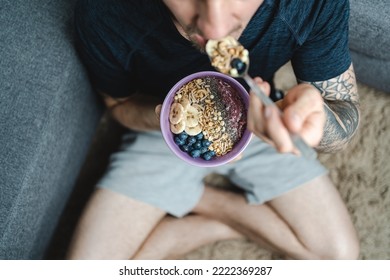 Close Up Top View Of Young Man Eating Granola And Smoothie Bowl With Fruit And Nuts. Healthy Eating Concept. Selective Focus, Unrecognizable Person