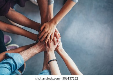 Close up top view of young people putting their hands together. Friends with stack of hands showing unity and teamwork. - Shutterstock ID 506137132