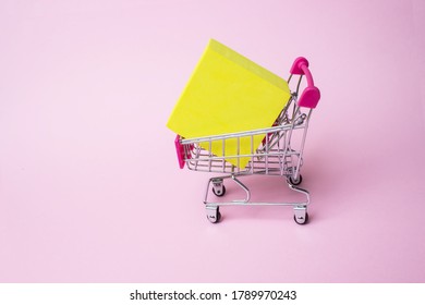 Close up toy metal shopping cart with red plastic handle and yellow box inside on pink background. Mock up header leave space for adding text or design for promote business campaign on line - Powered by Shutterstock