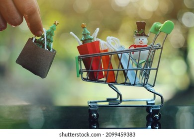 close up toy shopping cart with small bag, toy pine tree and snowman on table, merrychristmas and happy new year, saving and manage money for holiday sale season business, economic crisis problem
