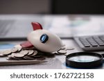 Close up of toy spacecraft, scattered coins, calculator and magnifier on office table