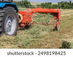 Close up of tractor baling hay using baler on summer day