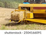 Close up of tractor baling hay using baler on summer day