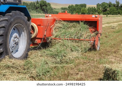Close up of tractor baling hay using baler on summer day