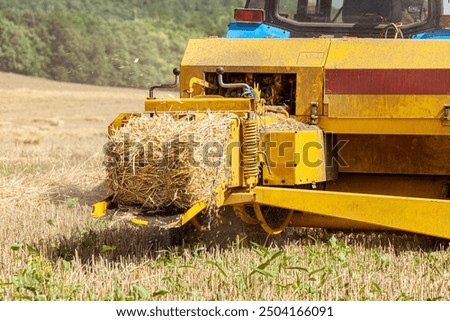 Close up of tractor baling hay using baler on summer day