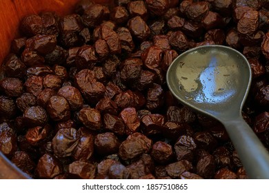 Close up traditional artisanal pickled sun cured black olives and scoop in a rustic natural wooden barrel on retail display of open market, high angle view - Powered by Shutterstock