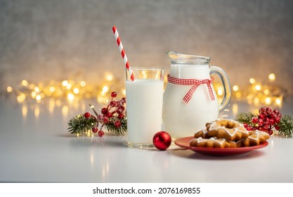 Close up traditional christmas milk in glass, jug with cookies on Christmas lights background, selective focus.
