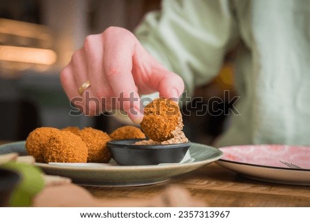 Close up of traditional Dutch bitterballen being dipped in mustard in a café restaurant