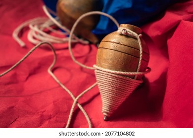 Close Up Of Traditional Wooden Spinning Top From Ecuador With His String Rope, On A Blue And Red Textured Background. Typical Games. Quito's Festivities Concept.