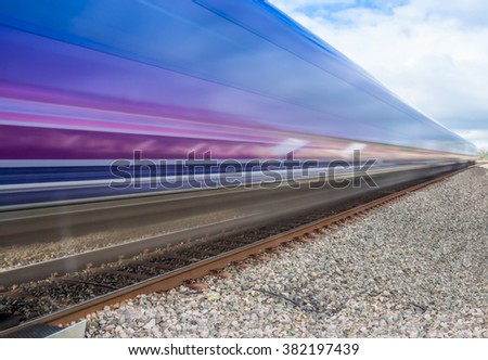 Close up of train speeding through English countryside on bright sunny day with extended exposure for extended   motion blur