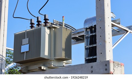 Close Up The Transformer On A Concrete Pole. Three-phase Transformers And Rafts On Rails For Industrial Plants On A Blue Sky Background. Selective Focus