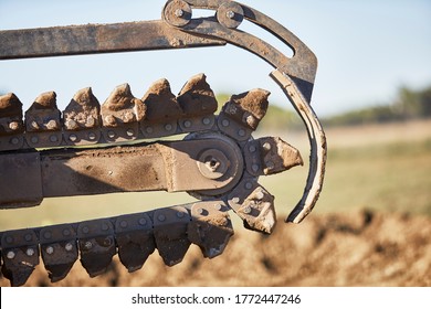 Close Up Of A Trencher Chain In Motion Preparing To Dig A Trench In Dirt